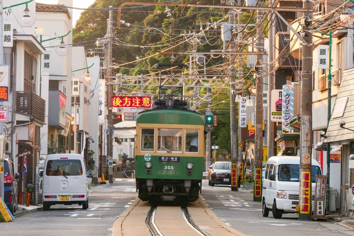 Green Enoden train running along a Kamakura street on a Kamakura and Enoshima day trip from Tokyo