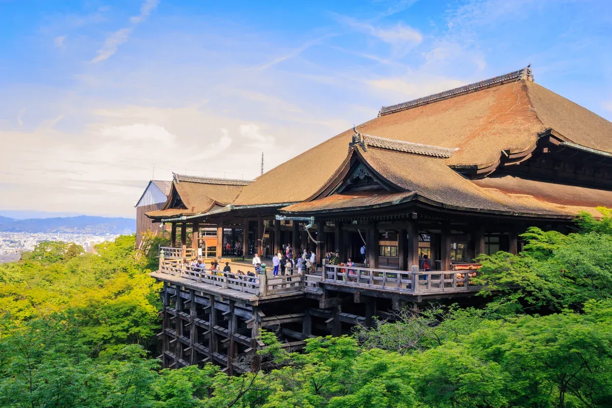 Kiyomizu-dera wooden stage above green trees in Kyoto on a Kyoto day trip from Tokyo by bullet train